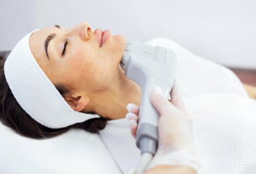 Femeie întinsă pe masă de tratament într-un spa, primind îngrijire facială